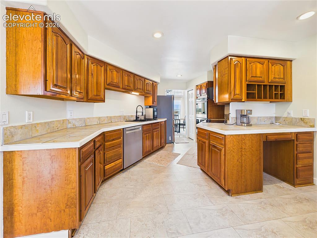 Image 5 of 50: Well-appointed kitchen showcases abundant wood cabinetry, expansive counter