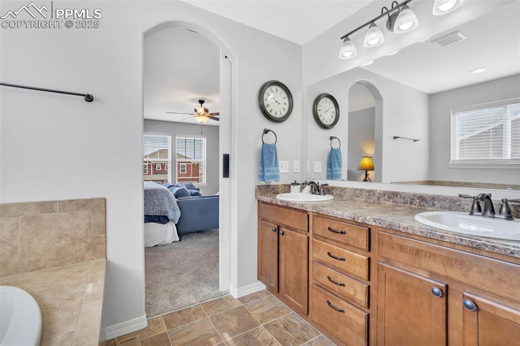 Image 19 of 50: Ensuite bathroom with a sink, ensuite bath, and double vanity