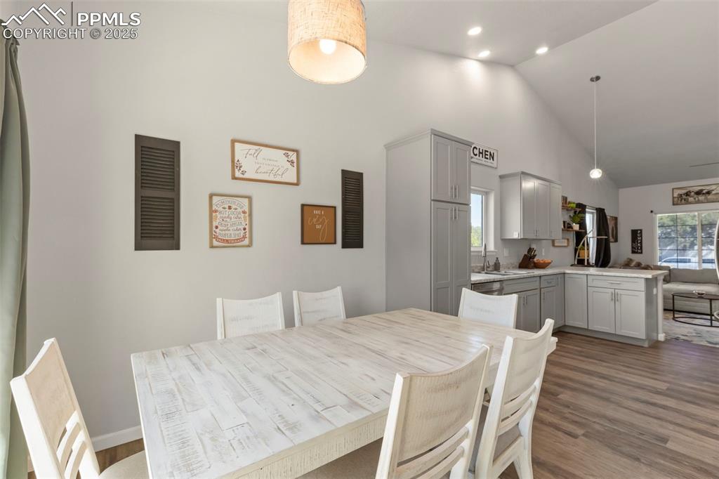 Image 13 of 23: Dining space with wood finished floors, high vaulted ceiling, and plenty of