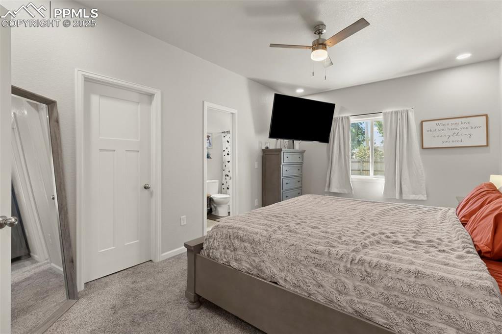 Image 15 of 23: Bedroom with carpet floors, a ceiling fan, and ensuite bath