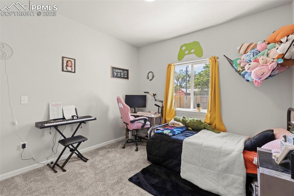 Image 20 of 23: Carpeted bedroom with a desk and baseboards