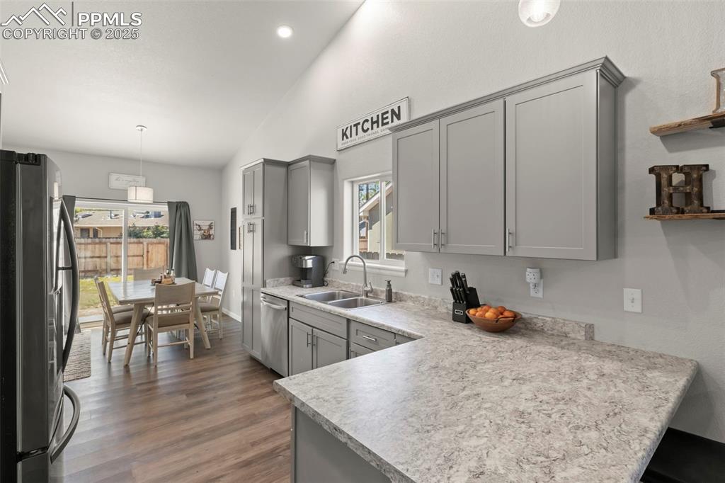 Image 9 of 23: Kitchen featuring gray cabinetry, a peninsula, appliances with stainless st
