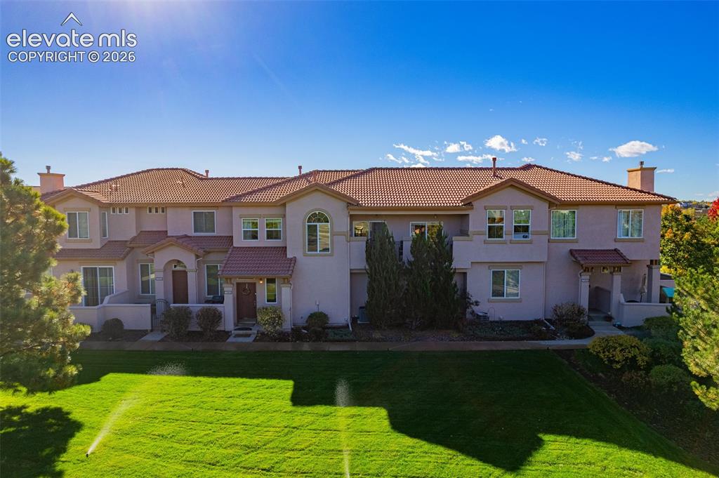 Caption: Multi-level stucco exterior featuring a clay tile roof, arched entryway accents, second-story balcon