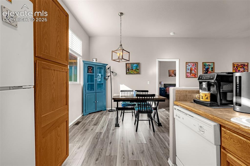 Image 11 of 27: Wood-finish flooring, geometric-frame pendant lighting, and neutral wall to