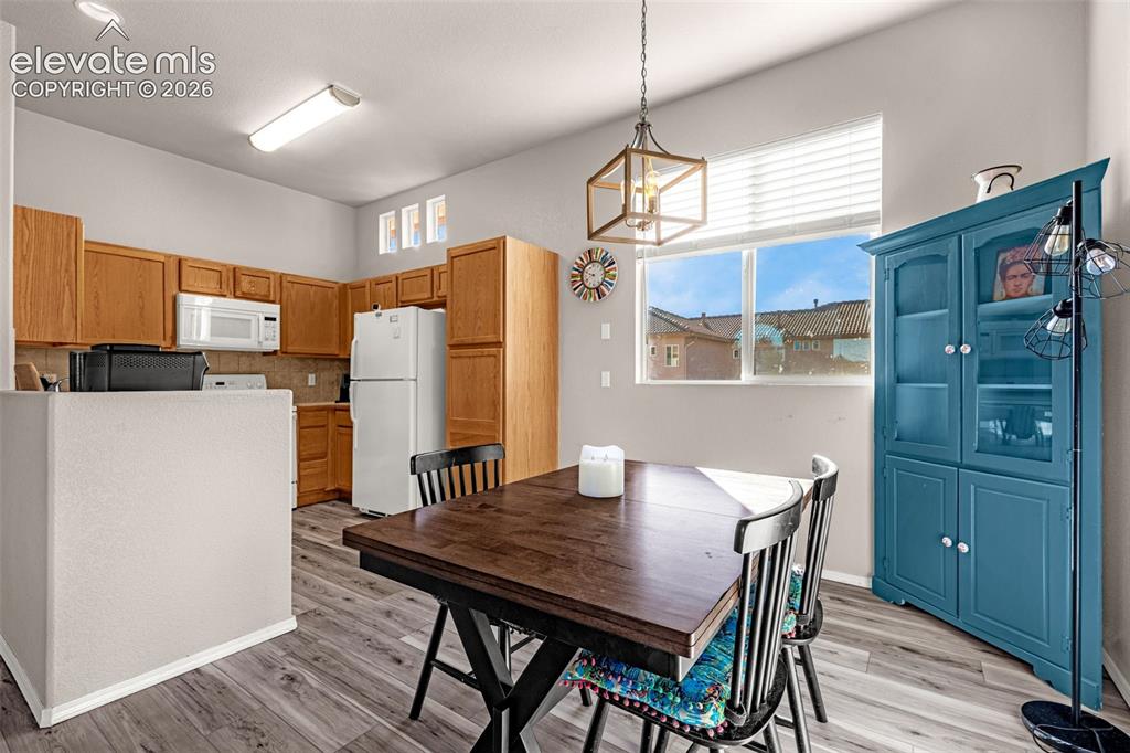 Image 12 of 27: Kitchen featuring wood cabinetry, white appliances, wood-finish flooring, a