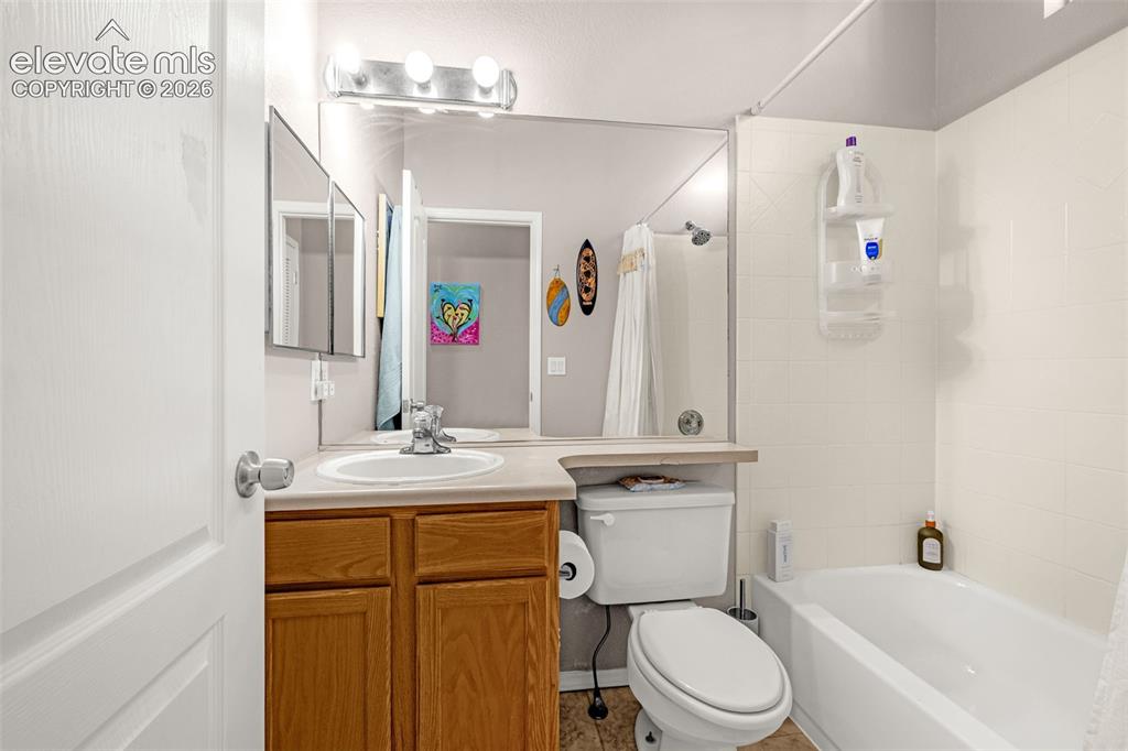 Image 16 of 27: Bathroom featuring a wood-finish vanity, solid-surface countertop with an i