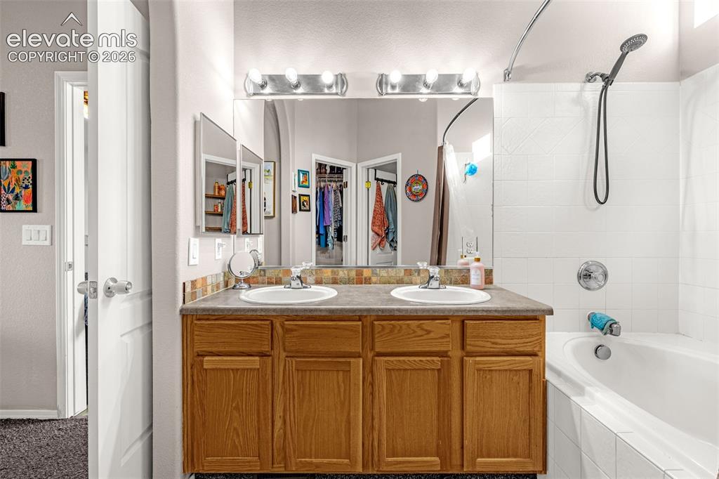 Image 18 of 27: Bathroom featuring a dual-sink vanity with natural wood cabinetry, a decora