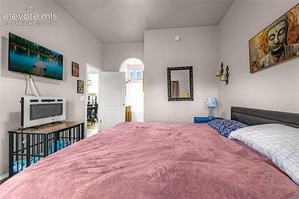 Image 20 of 27: Room featuring vaulted ceilings, a prominent arched doorway, neutral wall f