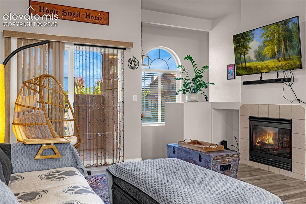 Image 5 of 27: Fireplace with tiled surround, arched window, and sliding glass door