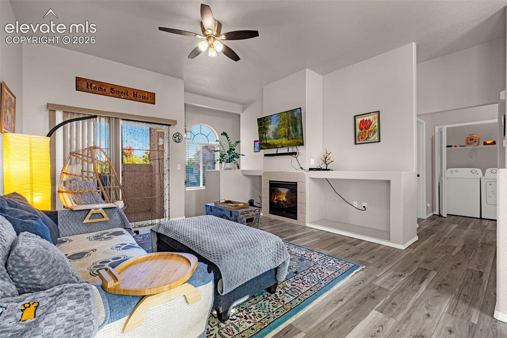 Image 7 of 27: Living area featuring wood-finish flooring, a fireplace with tile surround,
