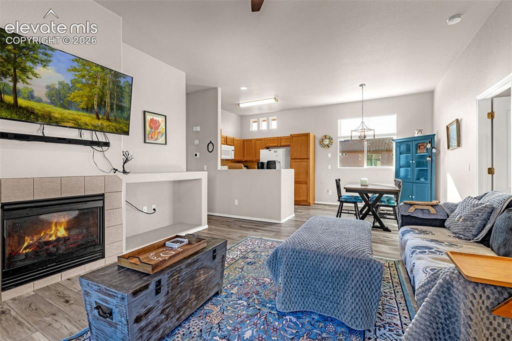 Image 8 of 27: Living area featuring a fireplace with neutral tile surround, built-in rece