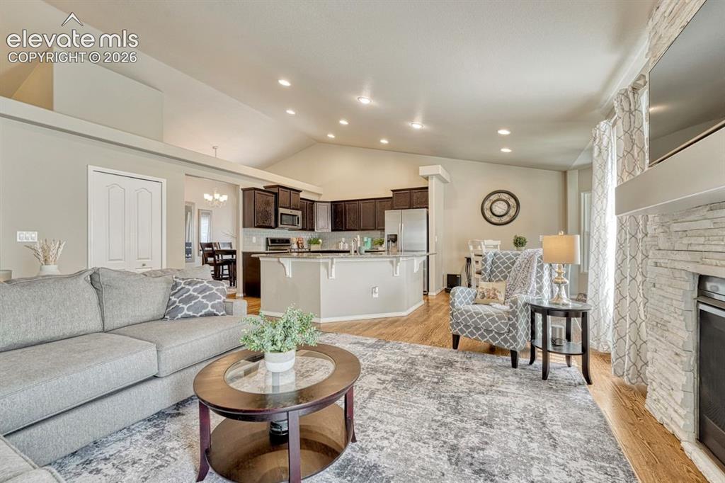 Image 13 of 50: Open-concept living area featuring vaulted ceilings, wood flooring, and a s