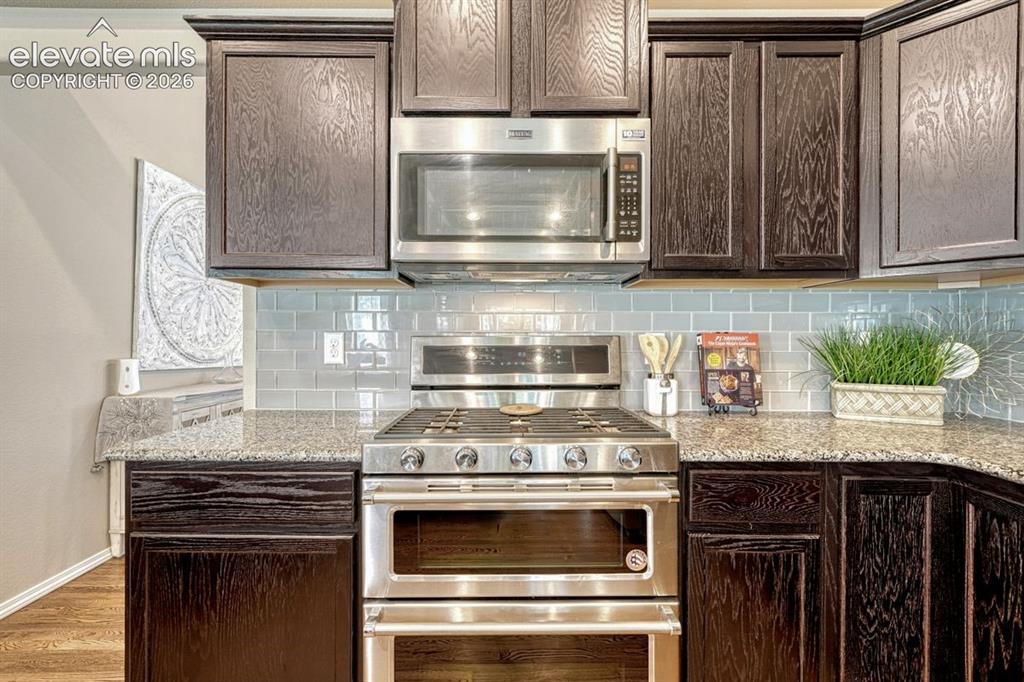 Image 17 of 50: Kitchen featuring dark wood-finish cabinetry, stainless steel appliances, g