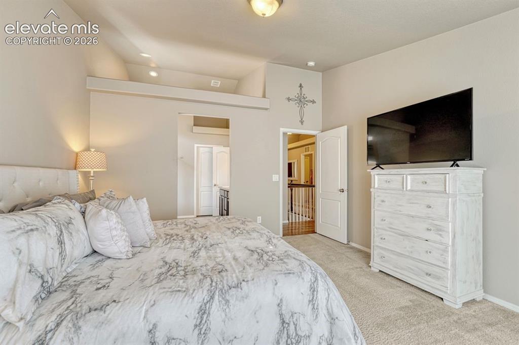 Image 26 of 50: Carpeted room featuring a vaulted ceiling with recessed lighting, an open d