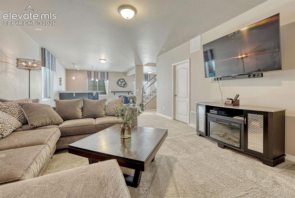 Image 33 of 50: Carpeted living area featuring a wall-mounted television and built-in elect