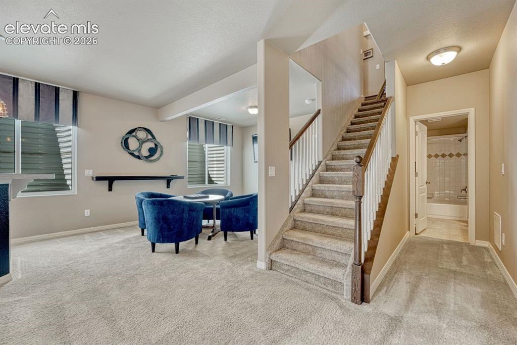 Image 34 of 50: Carpeted staircase with white balusters and a wood-finish handrail, complem