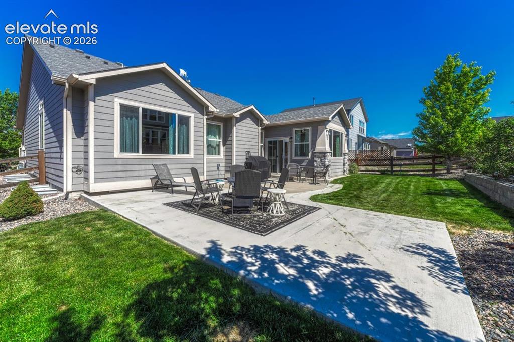 Image 43 of 50: Expansive concrete patio area with a manicured lawn
