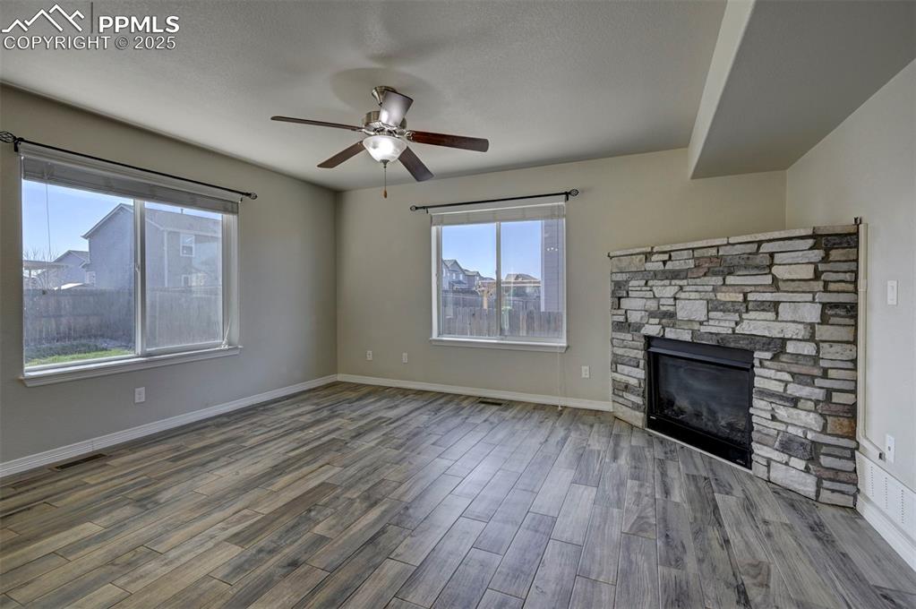 Image 12 of 50: Unfurnished living room featuring ceiling fan, visible vents, a fireplace, 