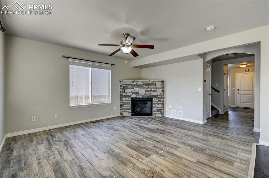 Image 13 of 50: Unfurnished living room with baseboards, a ceiling fan, arched walkways, an