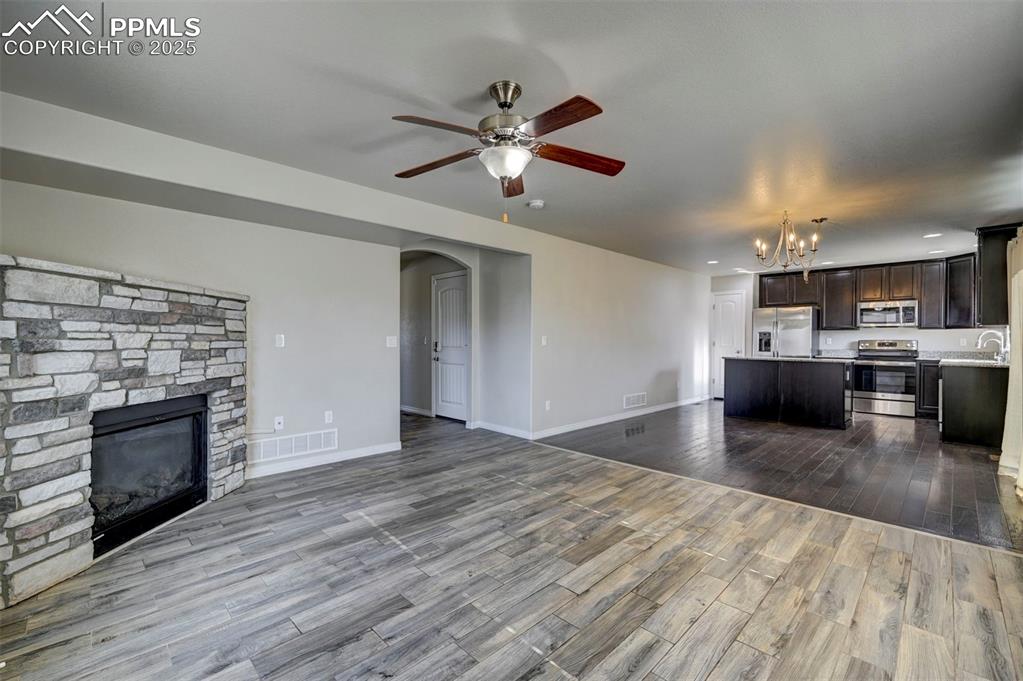 Image 14 of 50: Unfurnished living room featuring dark wood-style flooring, a fireplace, ar