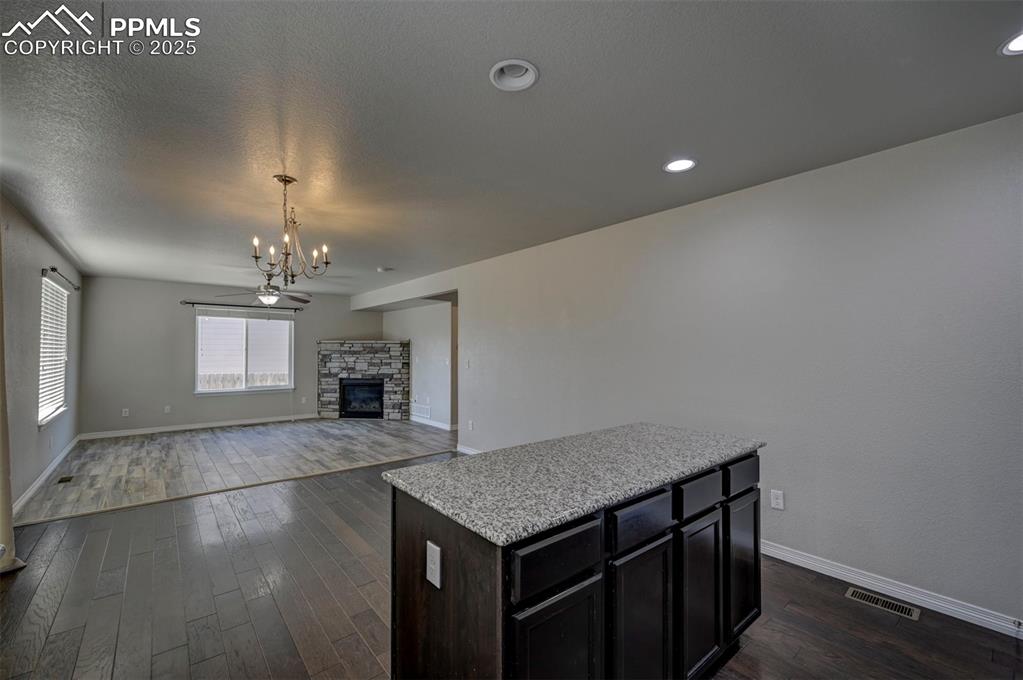 Image 21 of 50: Unfurnished living room featuring a stone fireplace, visible vents, baseboa