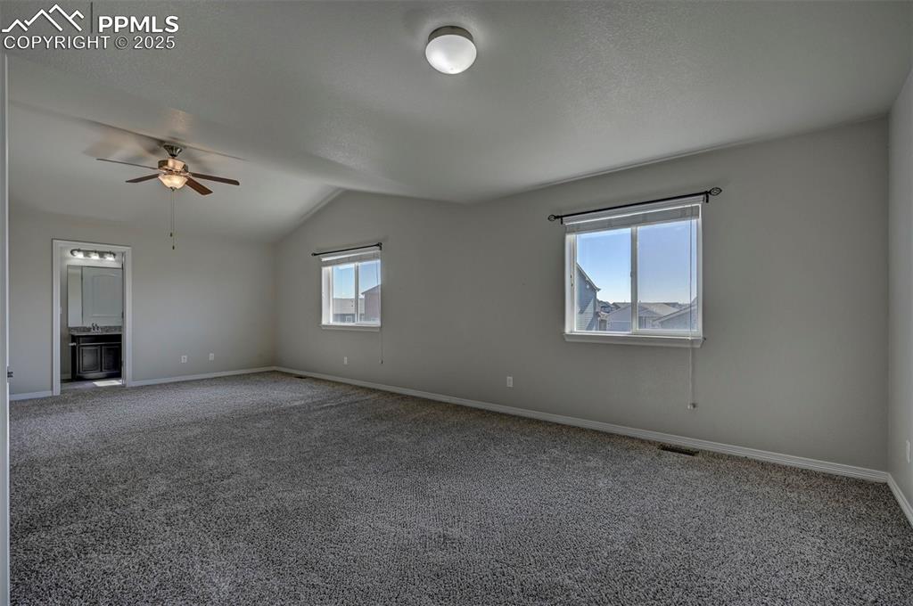 Image 24 of 50: Unfurnished room with a ceiling fan, baseboards, lofted ceiling, and carpet