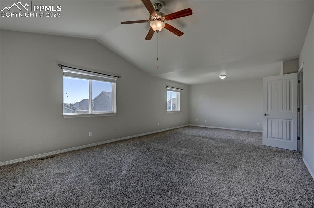 Image 26 of 50: Carpeted spare room with baseboards, ceiling fan, visible vents, and lofted