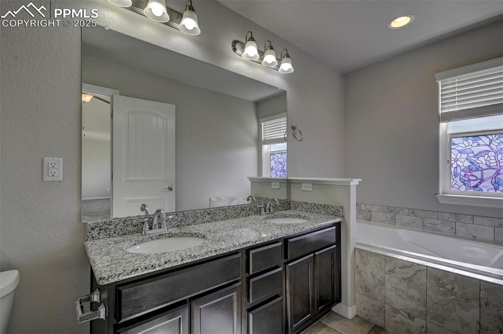 Image 29 of 50: Bathroom with double vanity, a wealth of natural light, a sink, and a garde