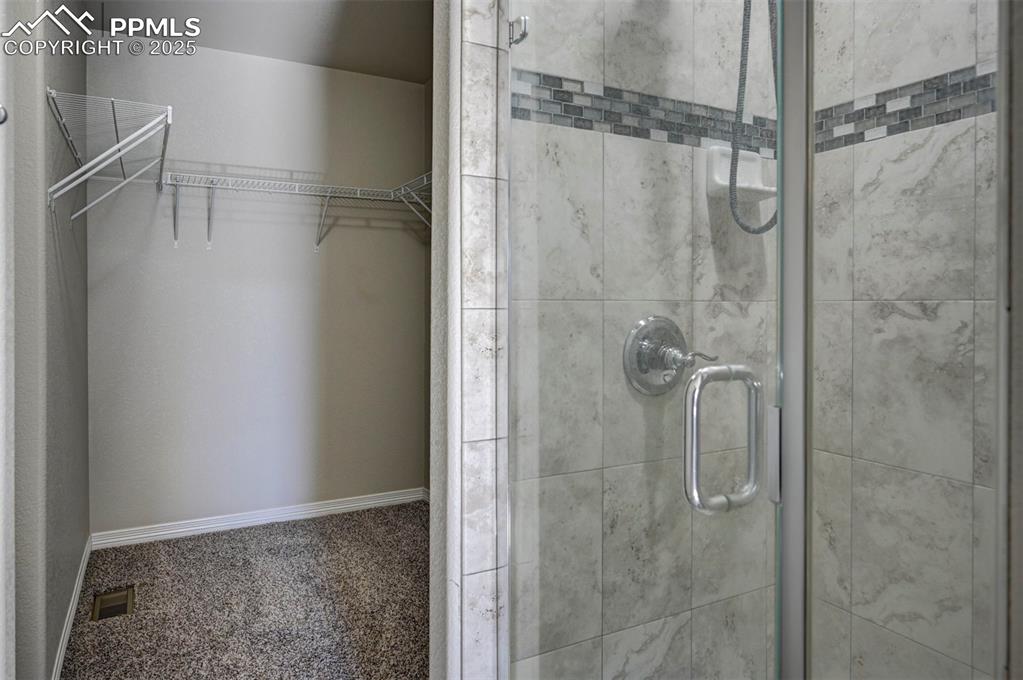 Image 30 of 50: Full bathroom with visible vents, a walk in closet, and a stall shower