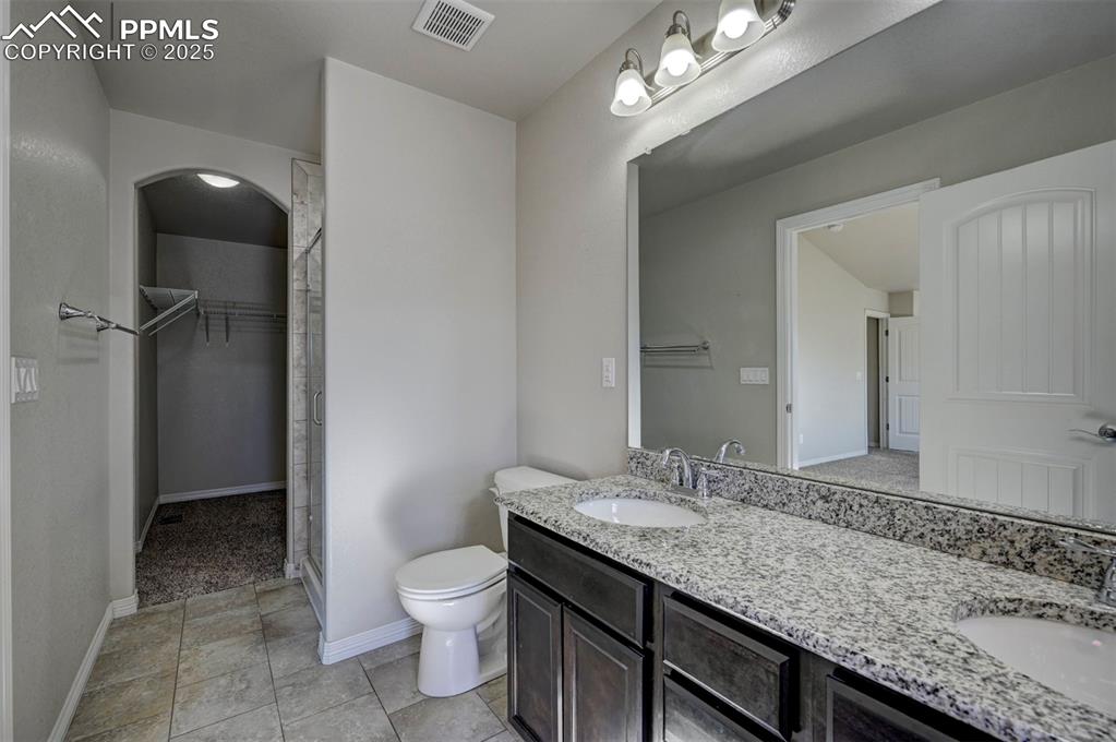 Image 32 of 50: Bathroom featuring toilet, visible vents, a sink, and a spacious closet