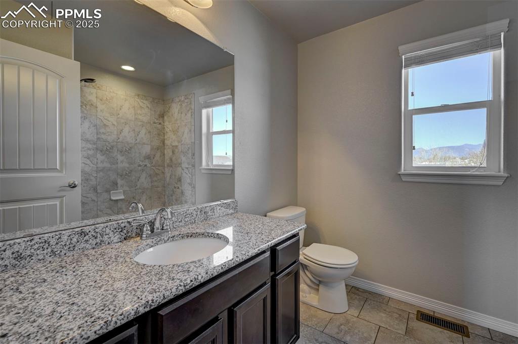 Image 34 of 50: Bathroom featuring visible vents, a tile shower, baseboards, vanity, and to