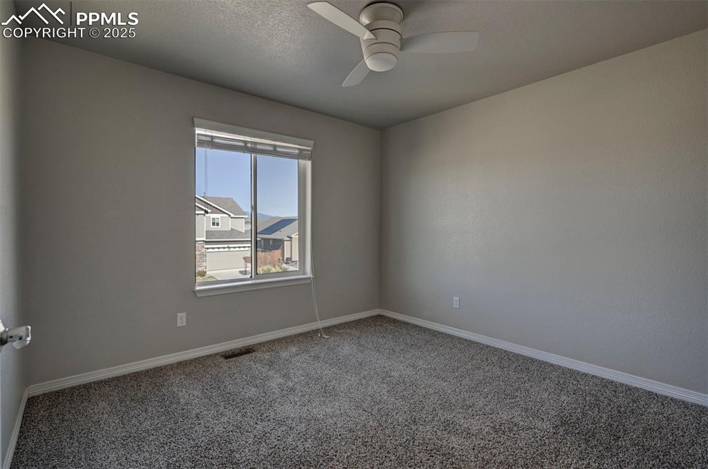 Image 35 of 50: Empty room with carpet floors, ceiling fan, visible vents, and baseboards
