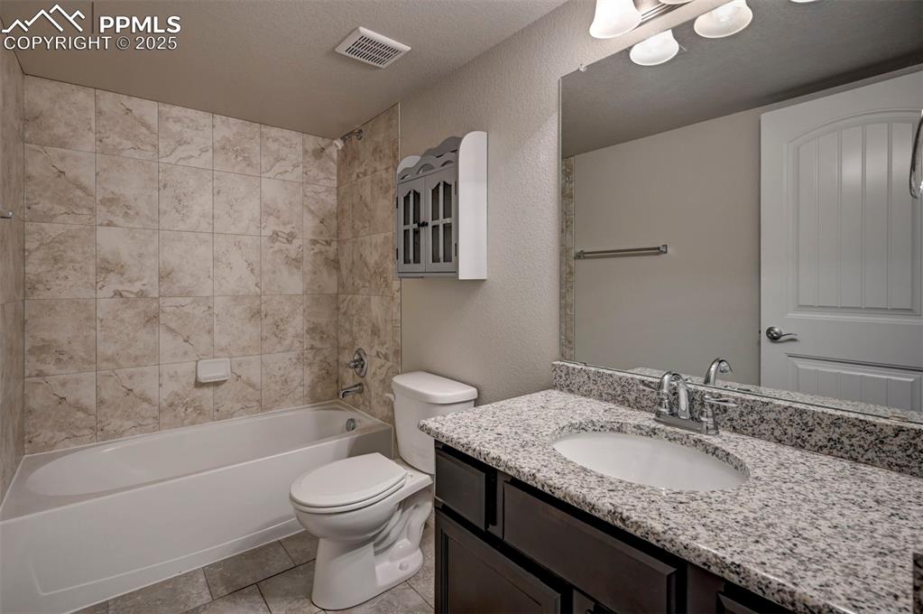Image 44 of 50: Full bath with visible vents, tile patterned flooring, vanity, toilet, and 