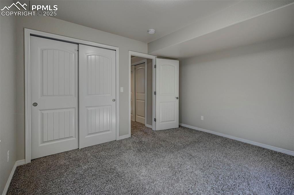Image 45 of 50: Unfurnished bedroom with baseboards, carpet, and a closet