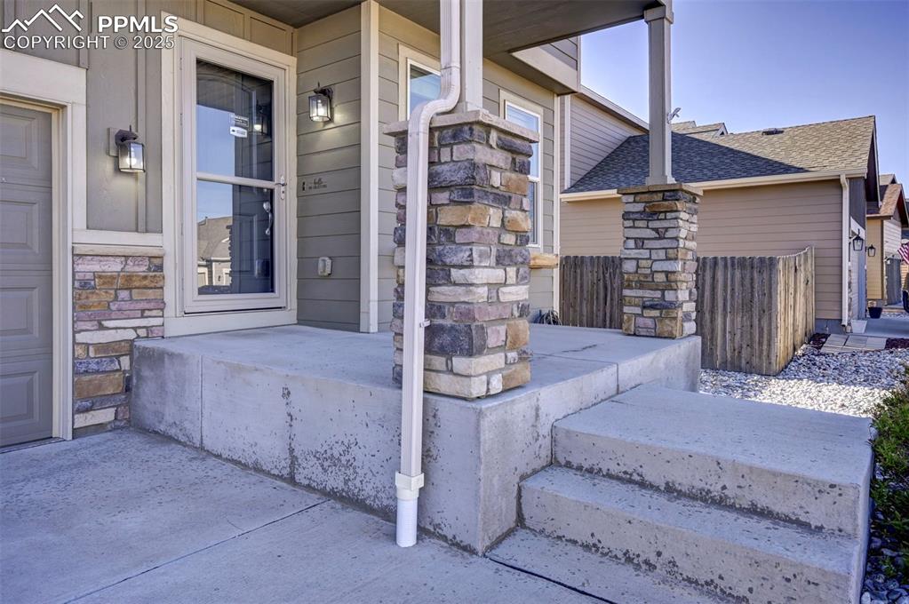 Image 5 of 50: Property entrance featuring roof with shingles, covered porch, and stone si