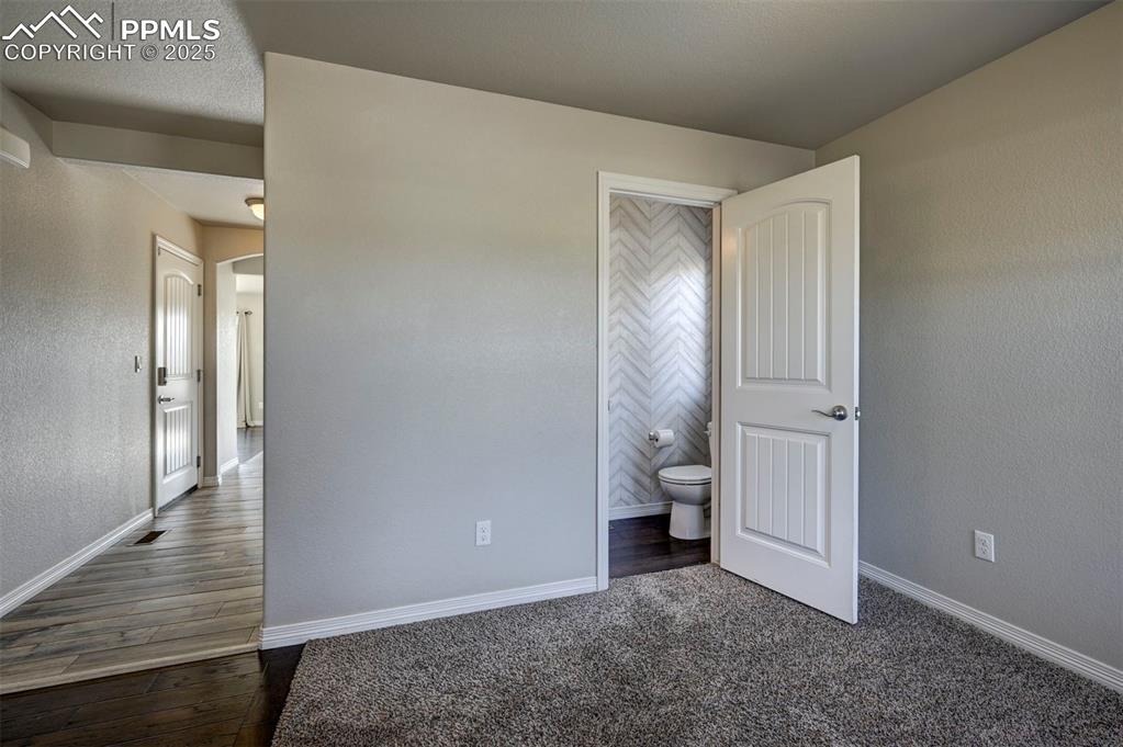 Image 9 of 50: Unfurnished bedroom featuring baseboards, dark wood-style flooring, and ens