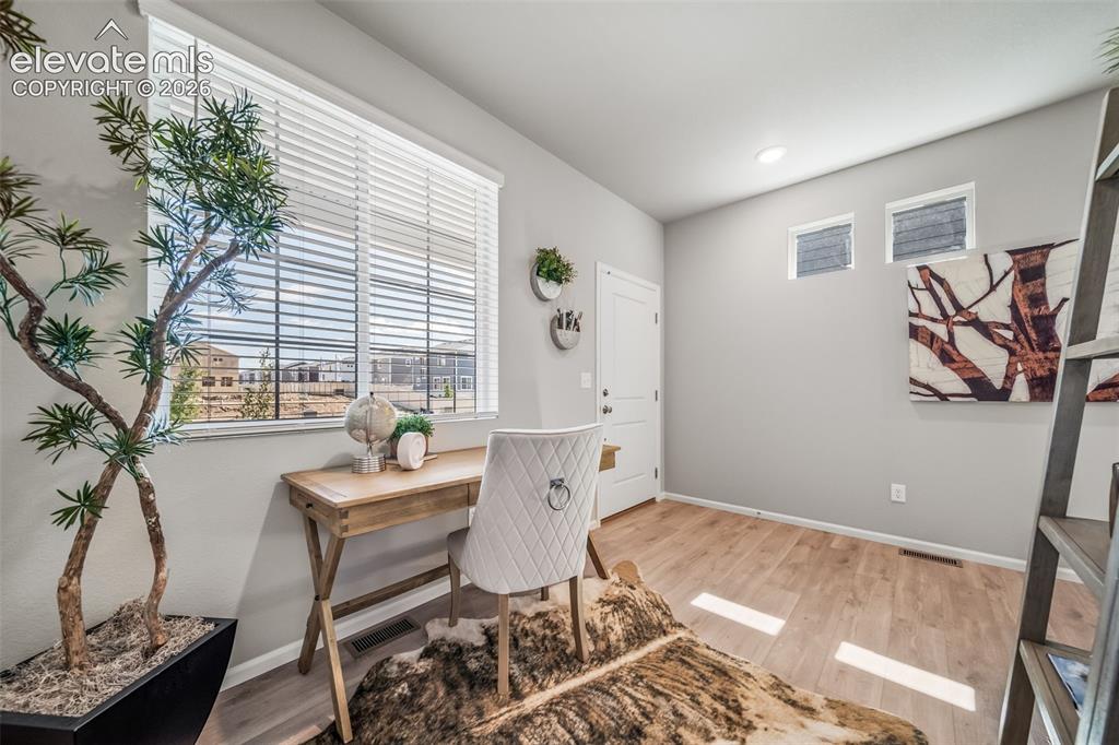 Image 12 of 21: Bright room featuring a large window with blinds, light wood-finish floorin
