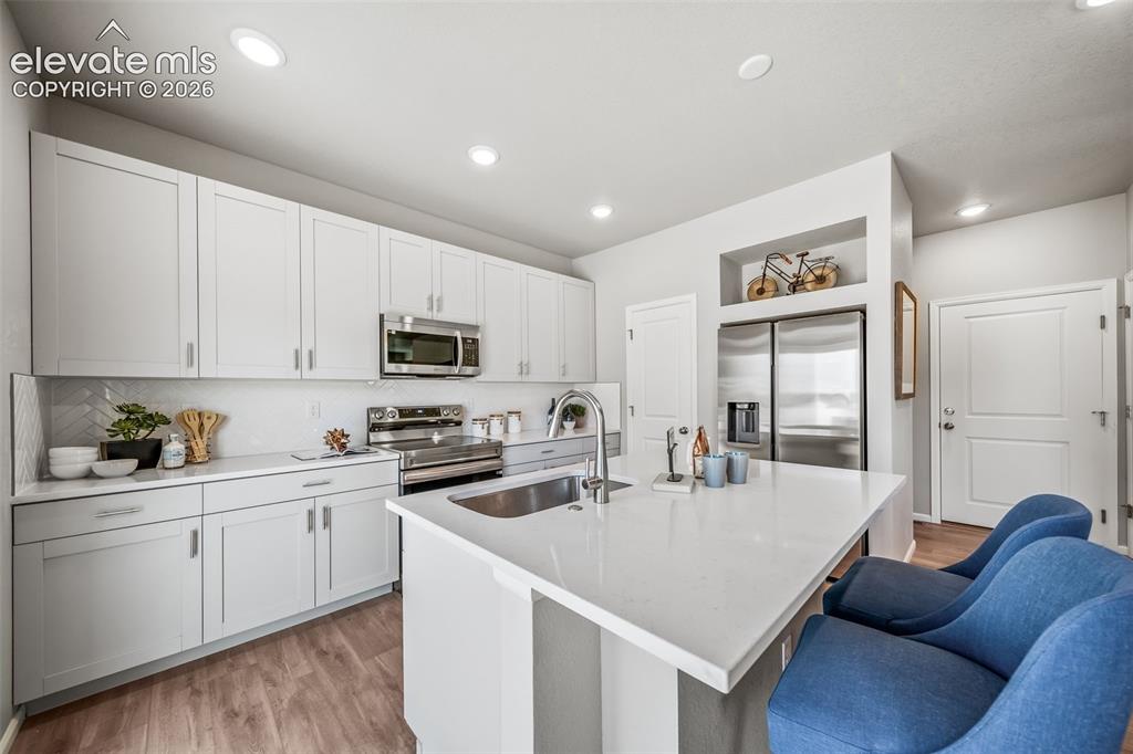 Image 15 of 21: Modern kitchen featuring light cabinetry with brushed nickel hardware, a la