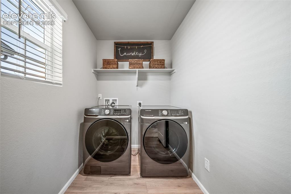 Image 16 of 21: Dedicated laundry area featuring wood-finish flooring, a window with blinds