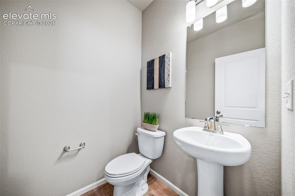 Image 17 of 21: Pedestal sink with chrome faucet, large vanity mirror, and three-bulb vanit
