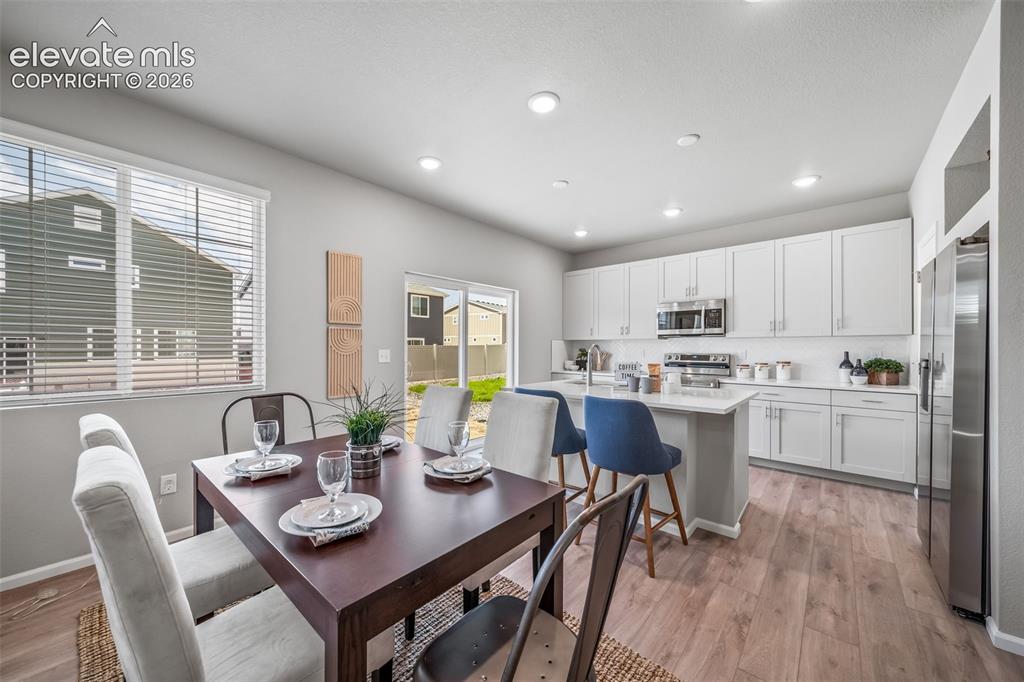 Image 7 of 21: Open-concept kitchen and dining area featuring light wood-finish flooring, 