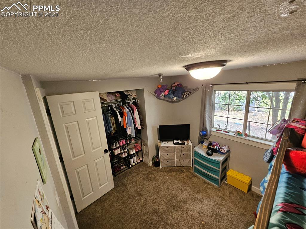 Image 14 of 23: Carpeted bedroom with a textured ceiling and a closet