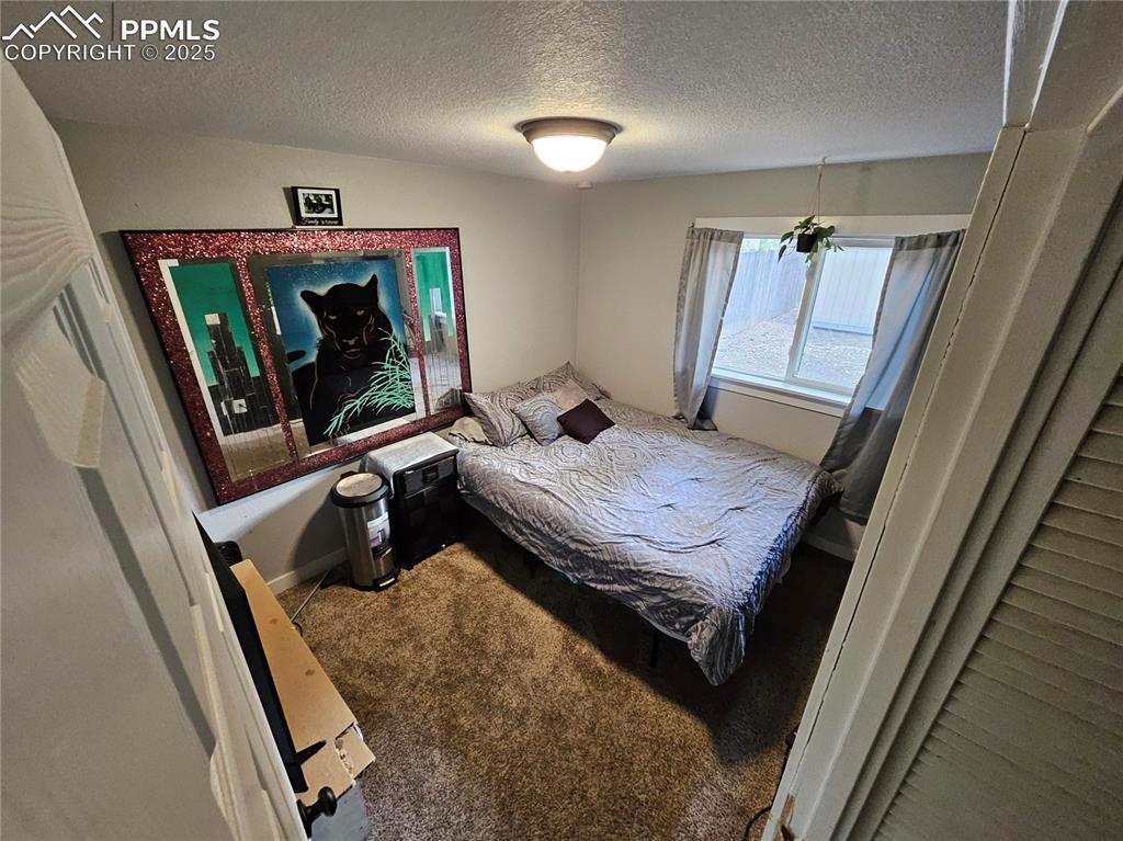 Image 16 of 23: Carpeted bedroom with a textured ceiling and baseboards
