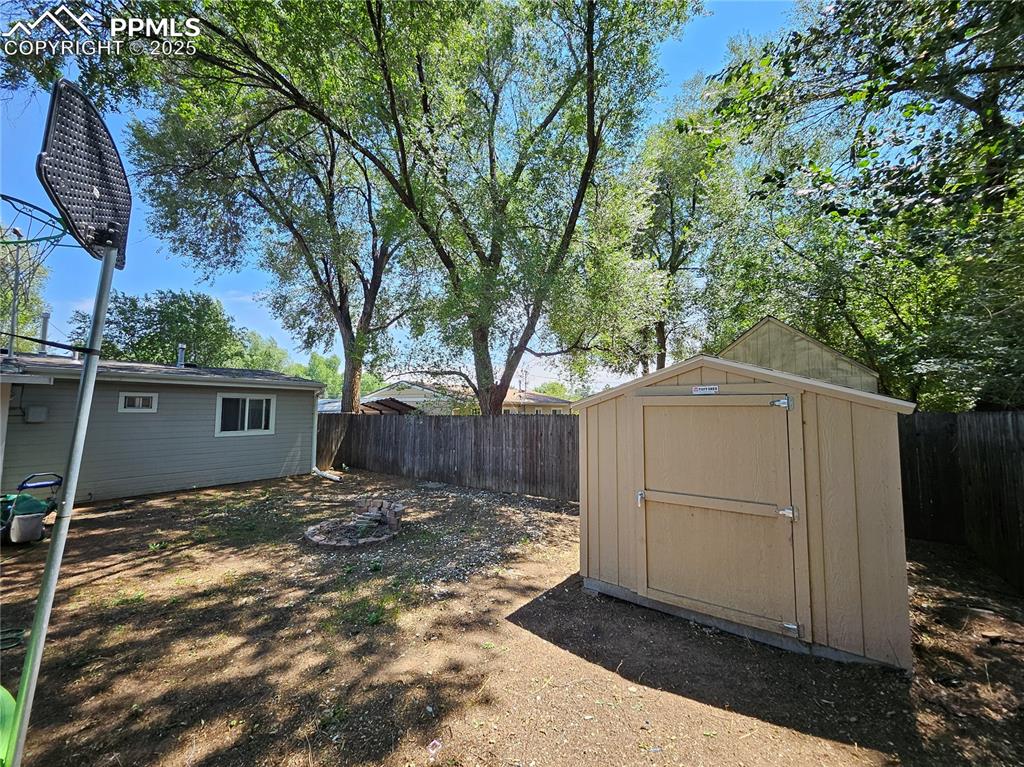 Image 22 of 23: Fenced backyard with a storage unit