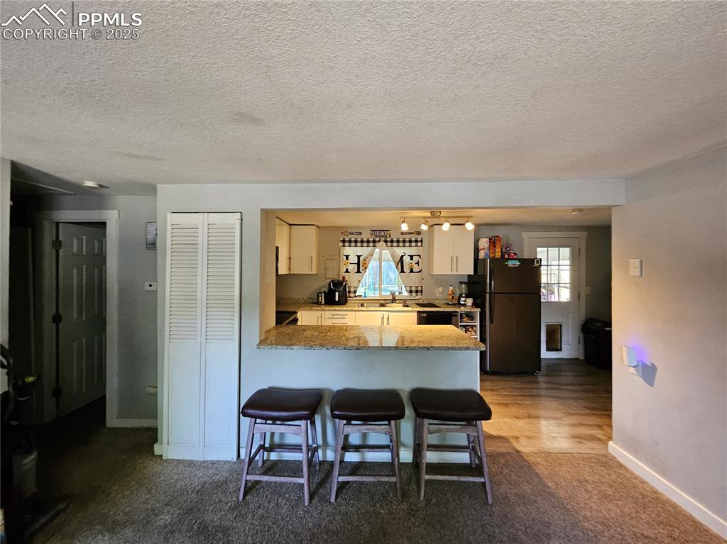 Image 4 of 23: Kitchen featuring freestanding refrigerator, a breakfast bar area, a penins