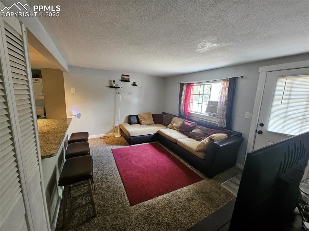 Image 5 of 23: Carpeted living area with a textured ceiling