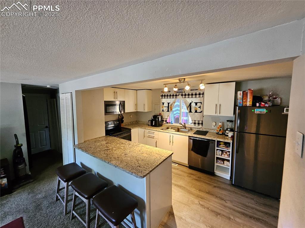 Image 7 of 23: Kitchen with appliances with stainless steel finishes, a textured ceiling, 