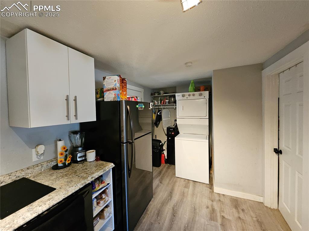 Image 9 of 23: Kitchen with estacked washer and dryer, a textured ceiling, light wood fini