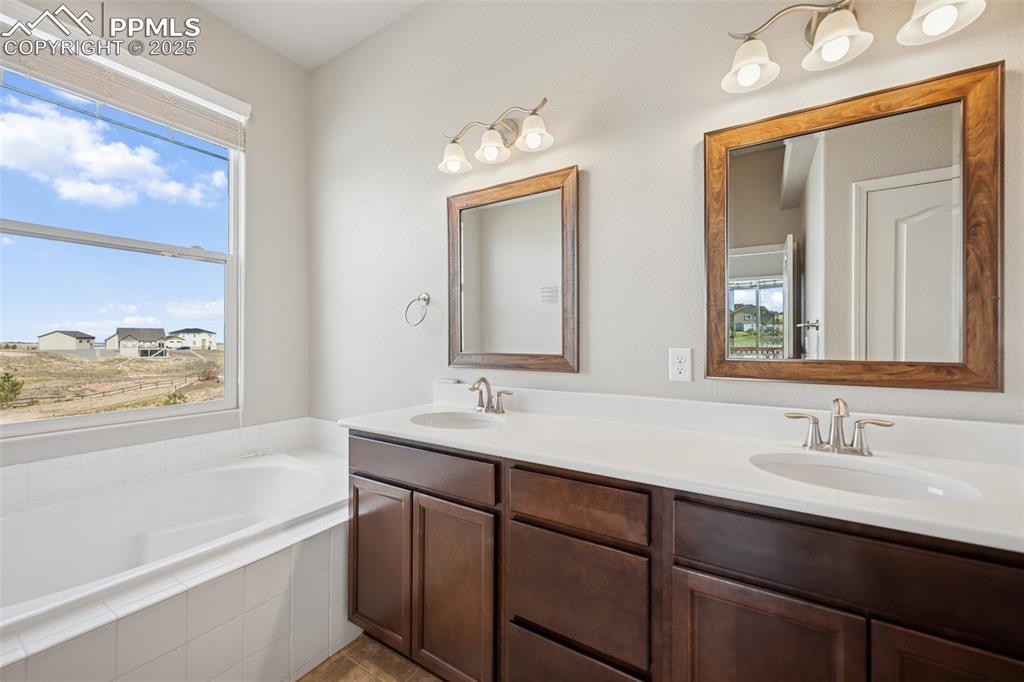 Image 11 of 38: Bathroom featuring double vanity, a sink, and a garden tub