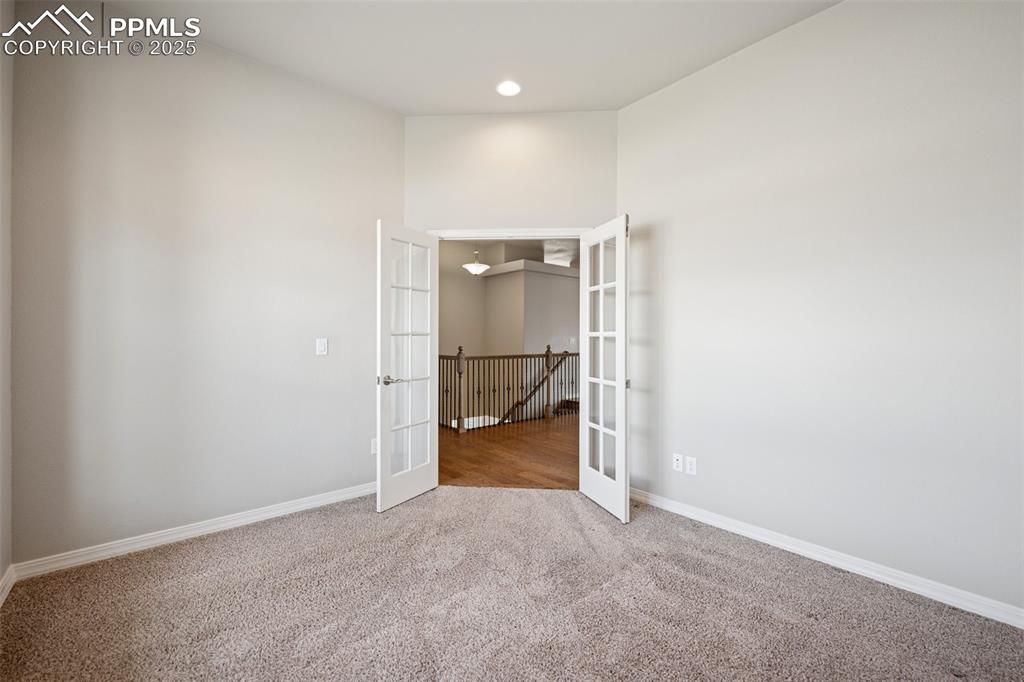 Image 13 of 38: Office with large picture window, french doors and carpet. Alcove can be us